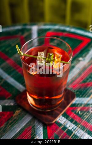 Ein transparenter Cocktail in einem Longdrinkglas mit einem großen Eiswürfel, garniert mit Gummibären Stockfoto