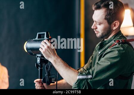 Junge kreative Fotograf Steuerung des Lichts im Studio, close up Seitenansicht Foto. Job, Beruf Stockfoto
