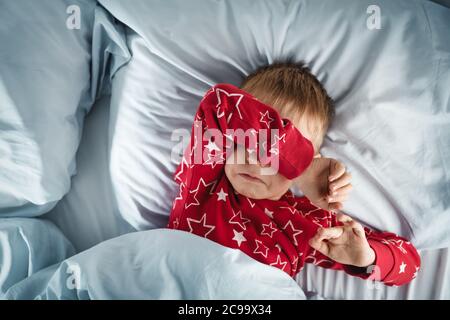 Schlafender Junge im Bett mit blauen Bettungen Stockfoto