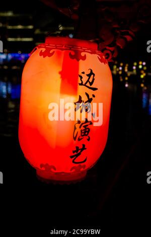 Feng Huang, China - August 2019 : Rote, gelbe und orange Laterne mit chinesischen Schriftzeichen hängen auf den alten historischen hölzernen Touristenbooten in Stockfoto