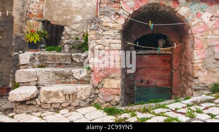 Eine typische Straße des alten Dorfes Torella del Sannio in Molise, mit einigen Stufen, einem Blumentopf und einer grünen und braunen Tür Stockfoto