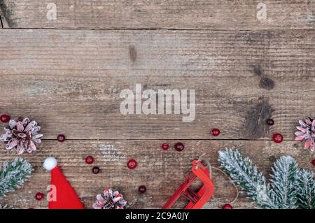 Weihnachtsbaum, Zapfen, Schlitten, Beeren und Weihnachtsmütze. Stockfoto