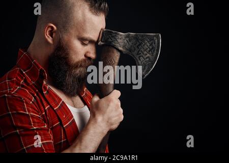 Ernsthafte Holzfäller. Zuversichtlich bärtiger Mann verbunden Ax zur Stirn Stockfoto