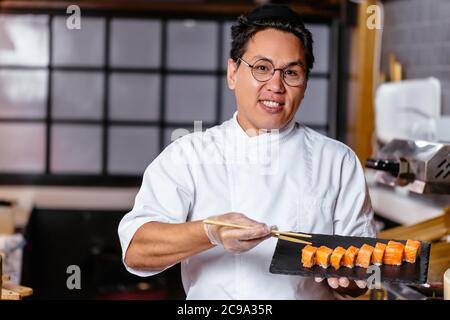 Attraktive Meisterkoch bietet neue Art von Sushi schmecken. Freundlichkeit, Werbung für Sushi. Close up Foto Stockfoto