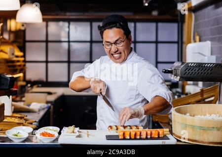 Nervöse Mann hat Angst vor dem Schneiden Sushi. Nahaufnahme Foto. Stockfoto