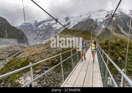 Hooker Valley Track Wanderweg, Neuseeland. Wanderer Menschen überqueren Brücke auf dem Hooker Valley Track, Aoraki, Mt Cook National Park mit Schnee Stockfoto