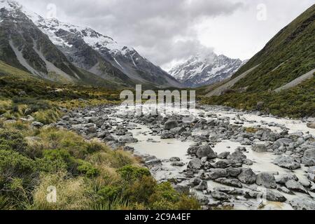 Hooker Valley Track Wanderweg, Neuseeland. Fluss, der zum Hooker See führt, mit Gletscher und Blick auf den Aoraki Mount Cook National Park mit schneebedeckter Aussicht Stockfoto