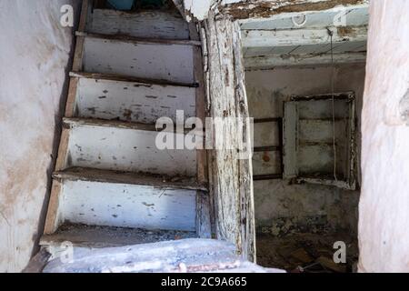 Ein bröckelndes Haus in Lamezia Terme, Italien. Bild durch das Fenster eines Treppenhauses und Blick auf das Erdgeschoss. Stockfoto