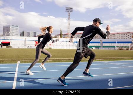 In voller Länge Seitenansicht Schuss. Sprinting Mann und Frau in der Arena. Geschwindigkeit und Bewegung Konzept. Mann und Frau versuchen, herauszufinden, wer die schnellste Runn ist Stockfoto