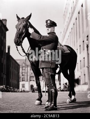 1930ER JAHRE UNIFORMIERTE MONTIERTE POLIZIST NEBEN SEINEM PFERD STEHEND BLICK AUF KAMERA ST. LOUIS MISSOURI USA - C1097 HAR001 HARS PERSONEN VEREINIGTE STAATEN VON AMERIKA FÜRSORGE MÄNNER AUFTRAG OFFIZIER VERTRAUEN NÄCHSTE AUSDRÜCKE B&W NORDAMERIKA COP AUGENKONTAKT NORDAMERIKA SCHÜTZEN SÄUGETIERE WELLNESS SEINE STÄRKE MUT UND NIEDRIGER WINKEL MISSOURI STERN STOLZ AUF AUTORITÄT BERUFE UNIFORMEN KONZEPTIONELLE STILVOLLE UNTERSTÜTZUNG UNIFORMIERTE OFFIZIERE POLIZISTEN POLIZISTEN POLIZISTEN SÄUGETIER MITTLEREN ERWACHSENEN MITTLEREN ERWACHSENEN MANN MONTIERT ZWEISAMKEIT ABZEICHEN SCHWARZ UND WEISS KAUKASISCHEN ETHNIZITÄT HAR001 MO ALTMODISCH STRENGEN ST. LOUIS Stockfoto