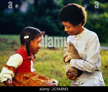 1970S AFRICAN-AMERICAN FRAU MUTTER SITZT IM HOF MIT LÄCHELNDEM KLEINEN MÄDCHEN TOCHTER UND HÄLT TABBY KITTEN CAT PET - KJ5638 PHT001 HARS GESICHTS KATZEN JUNGE ERWACHSENE FREUDE LEBENSSTIL ZUFRIEDENHEIT FRAUEN ZEIGEN ZU HAUSE LEBEN KOPIEREN RAUM FREUNDSCHAFT HALBE LÄNGE DAMEN TÖCHTER PERSONEN PFLEGE AUSDRÜCKE TABBY GLÜCK SÄUGETIERE AFRICAN-AMERICANS AFRO-AMERICAN UND EXTERIOR KATZE BLACK ETHNICITY VERBINDUNG KONZEPTIONELLE STILVOLLE KATZEN EINFÜHRUNG WACHSTUM JUGENDLICHE KITTY SÄUGETIER MÜTTER ZWEISAMKEIT JUNGE ERWACHSENE FRAU ALTMODISCHE AFROAMERIKANER Stockfoto