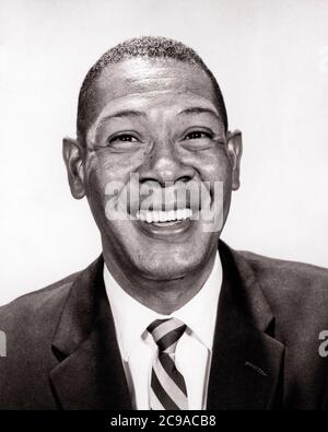 1960S PORTRAIT OF AFROAMERIKANER MAN LÄCHELND BREIT TRAGEN ANZUG UND KRAWATTE BLICK AUF KAMERA - N1600 HAR001 HARS AFROAMERIKANER UND SCHWARZE ETHNIZITÄT STOLZ LÄCHELT FRÖHLICH SCHWARZ UND WEISS HAR001 ALTMODISCHE AFROAMERIKANER Stockfoto