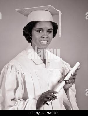 60S PORTRAIT LÄCHELND AFROAMERIKANISCHE FRAU HOCHSCHULABSOLVENT TRAGEN CAP UND KLEID HALTEN DIPLOM BLICK AUF KAMERA - N2035 HAR001 HARS FEIER FRAUEN DIPLOM GESUNDHEIT KOPIEREN RAUM HALBE LÄNGE DAMEN PERSONEN INSPIRATION VERTRAUEN AUSDRÜCKE B&W BLICKKONTAKT ERFOLG TRÄUME GLÜCK WELLNESS FRÖHLICH ABENTEUER STÄRKE SIEG UNIVERSITÄTEN AFRO-AMERIKANER MUT AFRO-AMERIKANER UND AUFREGUNG WISSEN FÜHRUNG LEISTUNGSSTARKE FORTSCHRITT SCHWARZ ETHNIZITÄT RICHTUNG STOLZ GELEGENHEIT LEISTUNG LÄCHELT HOCHSCHULBILDUNG KONZEPTIONELL FRÖHLICH STILVOLLE HOCHSCHULEN WACHSTUM JUNGE ERWACHSENE FRAU Stockfoto