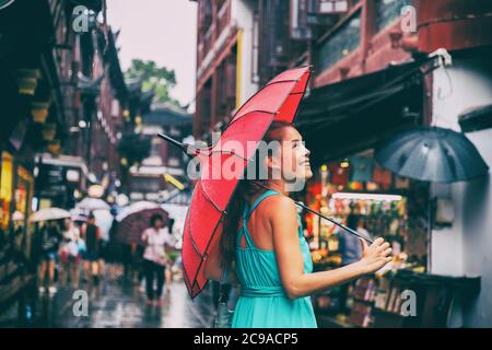 Menschen Lifestyle Regenschirm Reise asiatische Frau einkaufen in chinatown Marktstraße. Regentag Mädchen Tourist unter roten orientalischen Regenschirm in hinteren Gassen in Stockfoto