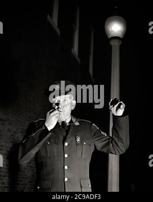 1950ER EINFUSS-PATROUILLE POLIZEI OFFIZIER SERGEANT IN UNIFORM IN DER NACHT BLICK AUF KAMERA HÄLT TASCHENLAMPE WEHT PFEIFE - P3523 CRS001 HARS OFFICER MITTLEREN ALTERS B & W MITTLEREN ALTERS MANN COP SCHÜTZEN UND DIENEN AUGENKONTAKT SCHÜTZEN TASCHENLAMPE ABENTEUER UND AUFREGUNG FÜHRUNG WARNUNG BEI BESETZUNGEN UNIFORMEN PATROUILLE STRASSENBELEUCHTUNG KONZEPTIONELLE ALARM OFFIZIERE POLIZISTEN STRASSE LAMPE BREITÄUGIGE POLIZISTEN MITTLEREN ERWACHSENEN MITTLEREN ERWACHSENEN MANN NACHT SERGEANT ABZEICHEN SCHWARZ UND WEISS ALTMODISCH Stockfoto