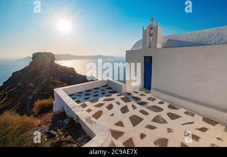 Orangefarbener Sonnenuntergang an einer weißen Kirche mit blauem Dor am Skaros Rock in Santorini, Griechenland Stockfoto