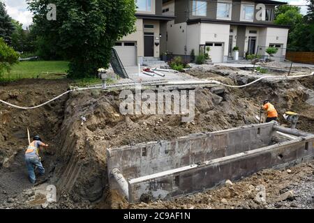 Arbeiter graben in einem Graben mit einem Grabenkasten für die Verlegung neuer Kanalrohre auf einer Wohnstraße in Nepean Ontario Stockfoto