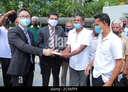 Colombo, Sri Lanka. Juli 2020. Anil Jasinghe (2. L, Front), der Generaldirektor des Gesundheitsdienstes in Sri Lanka, die Geschäftsleiter der chinesischen Botschaft Hu Wei (1. L, Front) und lokale Dreiradfahrer nehmen an einer Spendenzeremonie in Colombo, Sri Lanka, am 29. Juli 2020 Teil. Die chinesische Botschaft in Sri Lanka hat am Mittwoch eine große Anzahl von Gesichtsmasken und Plakaten gespendet, die das Bewusstsein für die COVID-19 Pandemie an eine führende Gewerkschaft von lokalen Dreiradfahrern schärfen. Quelle: Ajith Perera/Xinhua/Alamy Live News Stockfoto