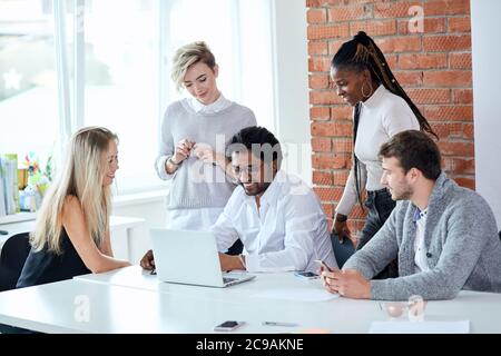 Netter Chef mit seinen Kollegen bei der Arbeit im Loft-Gebäude. Nahaufnahme Foto. Manager mögen ihren Job Stockfoto