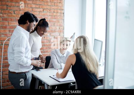 Klatschen junge Büroangestellte. Emloyees talling Witze miteinander während der Arbeit Stockfoto