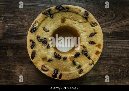 Hausgemachter Joghurt-Baumwollkuchen mit Mandelfrüchten, Cashewnüssen, Preiselbeeren, getrockneten Mangos, grünen Rosinen, auf rustikalem Holztisch Stockfoto