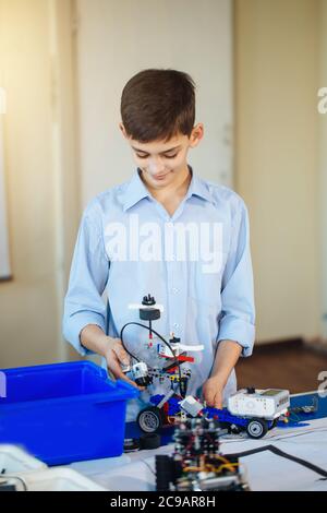 Smart clever Teenager eine selbstgebaute Roboter Bausatz an der Technischen laborotory mit, die in der Robotik Wettbewerb Stockfoto