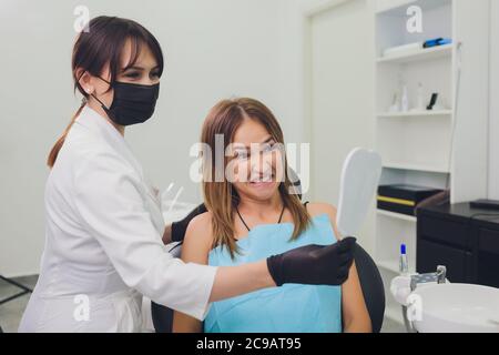 Die Patientin bewundert ihr Lächeln und schaut auf den Spiegel. Stockfoto