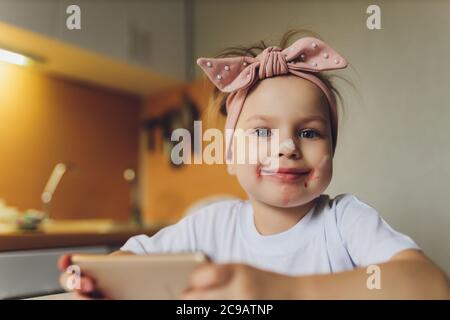 Mädchen essen am Tisch spielen am Telefon. Stockfoto