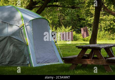 Ein Camping-Zelt vor der Wäsche trocknen zwischen Bäumen auf einem Campingplatz bei einem sonnigen Sommertag Stockfoto