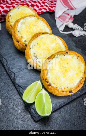 Köstliches libanesisches (arabisches) Essen, sfiha au Gratin mit Labneh und Käse auf schwarzem Schieferstein Hintergrund und traditionelle libanesische Keffiyeh. Stockfoto