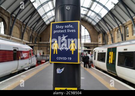 Ein Blick auf ein Coronavirus-Warnschild an der Kings Cross Station.die Regierung hat es zur Pflicht gemacht, Gesichtsbezüge an allen öffentlichen Verkehrsmitteln und an verschiedenen Orten wie Geschäften, Banken und Postämtern sowie Geschäften, Supermärkten, Indoor-Einkaufszentren und Bahnhöfen in England zu tragen. Stockfoto