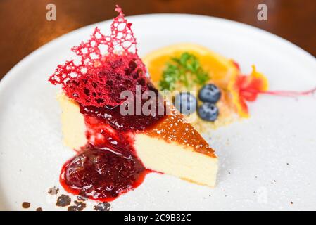 Käsekuchenscheibe mit Himbeersoße auf breitem Teller / Käsekuchen Obst leckeres Dessert Stockfoto