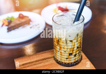 Bubble Milchtee im Glas auf dem Holztisch mit Kuchen / Taiwan Milchtee Stockfoto