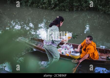 23 Jul 2020 - Frau, die Buddha im Boot im Hotel House of Passion in Amphawa Thailand Essen gibt. Stockfoto