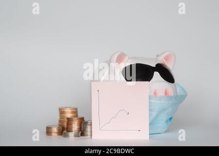 Der Zusammenbruch der Finanzmärkte und die Gefahr für finanzielle Ersparnisse aufgrund eines Pandemie-Virus.Masked Sparschwein Stockfoto