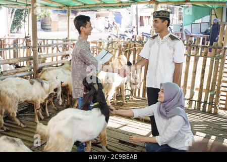 muslimische Menschen schütteln Hand mit Landwirt nach dem Kauf einer Ziege. idul adha Opferfest Stockfoto