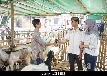 muslimische Menschen schütteln Hand mit Landwirt nach dem Kauf einer Ziege. idul adha Opferfest Stockfoto