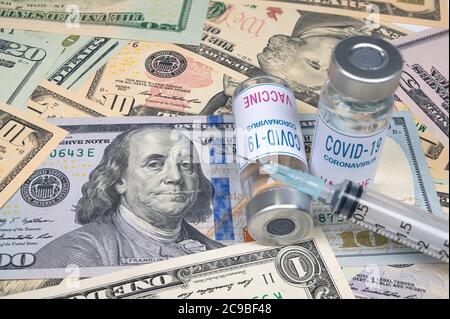 Spritzen und Covid-19-Impfampulle liegen auf dem US-Dollar. Stockfoto