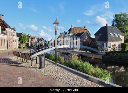 Die malerische Stadt Kollum in Friesland in den Niederlanden an einem sonnigen Sommerabend. Blick auf die Trekvaart Wasserstraße, Häuser am Wasser und die Pedes Stockfoto