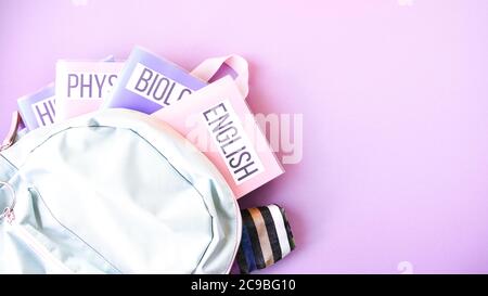 Flache Lage Zusammensetzung mit Rucksack und Schulbedarf und Themenbücher auf farbigem Hintergrund. Kopierraum Stockfoto