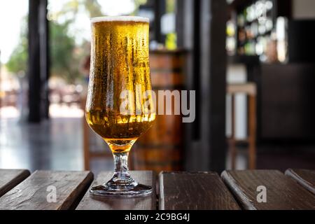 Ein Glas Bier auf einem Holztisch in einer Kneipe, Bar. Alkoholgetränk. Party, Freizeitkonzept Stockfoto