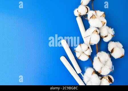 Menstruationstampons mit Baumwollblumen auf blauem Hintergrund. Konzept der kritischen Tage, Menstruation, Copy Space Stockfoto