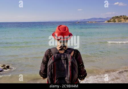 Schöne junge Frau in einem roten Hut am Strand Stockfoto