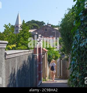 Rückansicht der schönen blonden jungen weiblichen Reisenden tragen Stroh Sonnenhut Sightseeing und genießen Sommerurlaub in einer alten traditionellen Küstenstadt Stockfoto