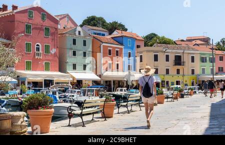 Rückansicht der schönen blonden jungen weiblichen Reisenden tragen Stroh Sonnenhut Sightseeing und genießen Sommerurlaub in einer alten traditionellen Küstenstadt Stockfoto