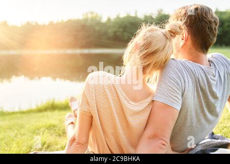 Verliebte Paare, die den Sonnenuntergang am See beobachten Stockfoto