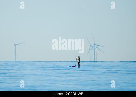 Worthing Beach, Worthing, Großbritannien. Juli 2020. Paddelboarder genießen die ruhige Morgensee. Mit einem klaren blauen Himmel und flachem Wasser genießen die Menschen auf Paddle Boards den frühen Morgen vor der Sussex-Küste. Der Windpark Rampion kann 13 km vor der Küste gesehen werden. Bild nach Kredit: Julie Edwards/Alamy Live Nachrichten Stockfoto