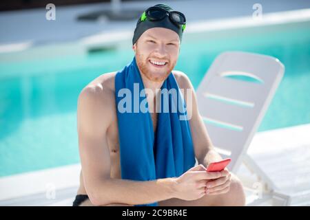 Glücklicher Mann in Badekappe auf der Sonnenliege am Pool Stockfoto