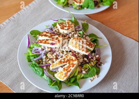 Frischer und gesunder Gemüsesalat mit gegrilltem Halloumi-Ziegenkäse darauf. Stockfoto