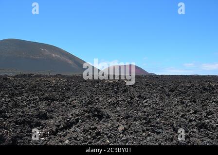 Die weite Leere und Einsamkeit der Lanzarote schwarz gefrorenen Lava vulkanischen Wüste und Vulkane im Hintergrund. Lanzarote, Kanarische Inseln. Spanien Stockfoto